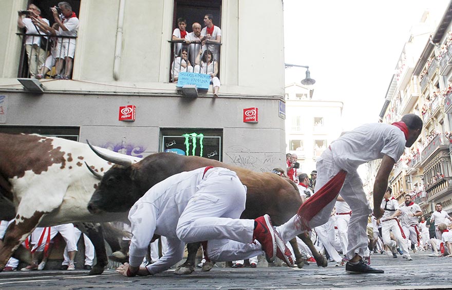 Un corredor se cae cerca de un toro de Jandilla en la peligrosa curva de los Mercaderes durante el inicio de la fiesta de San Fermín en Pamplona, Espa?a, el 7 de julio de 2015. Dos corredores fueron investidos por los toros a los 2 minutos y 23 segundos según la prensa local. [Agencias de fotografía]