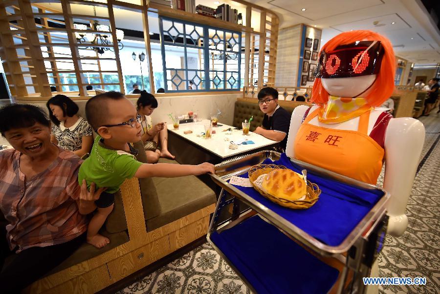 Un ni?o curioso toca a la camarera robot en Haikou, capital de la provincia de Hainan, el 3 de agosto de 2015. La camarerao robot trabaja en un restaurante de Haikou. [Foto/Xinhua]