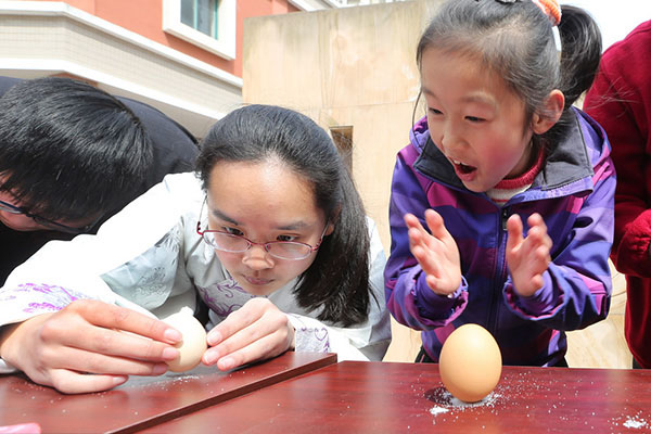 Los estudiantes de la Universidad de Nantong vestidos con trajes de la dinastía Han colocan huevos de pie en el barrio de Chongchuan, ciudad de Nantong, provincia de Jiangsu, el 20 de marzo de 2016.