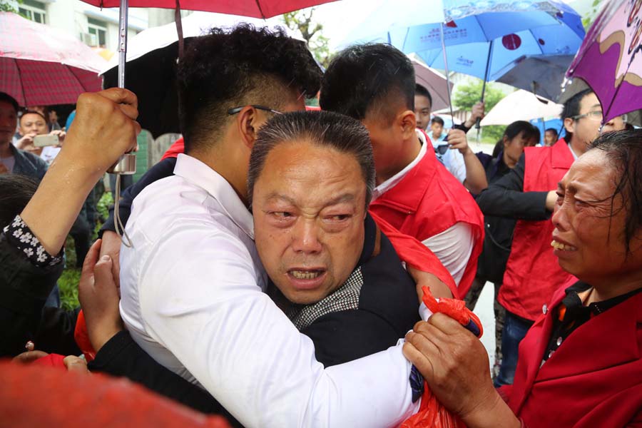 El padre de Tang lo abraza. 