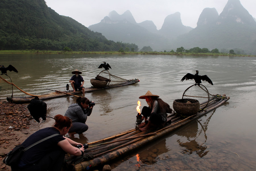 Visitantes de Australia fotografían a los dos ancianos sobre sus balsas de bambú en Guilin, región autónoma Zhuang de Guangxi. [Fotografía de Huo Yan/chinadaily.com.cn]