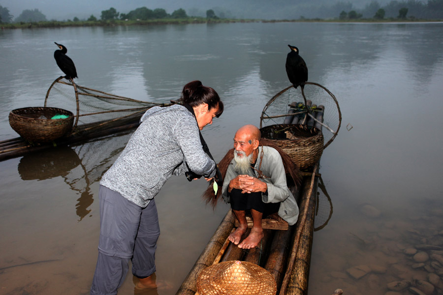 Una fotógrafa ense?a al anciano su foto en la cámara. [Fotografía de Huo Yan/chinadaily.com.cn]