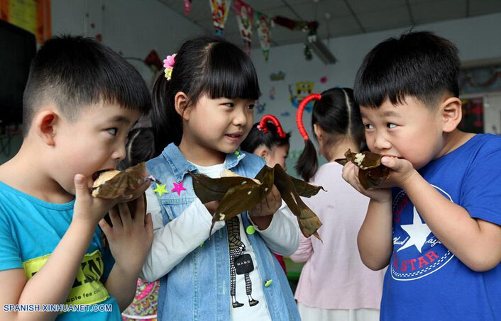  Li Qingji (i), Deng Jiahe (c) y Cao Heteng (d) comen Zongzi, una bola de masa de arroz glutinoso envuelta en holas de bambú u hojas rojas, con motivo del próximo Festival del Bote de Dragón o Duanwu en chino, en un jardín de ni?os en Zaozhuang, provincia de Shandong, en el este de China, el 8 de junio de 2016. El Duanwu se celebrará el 9 de junio este a?o. (Xinhua/Sun Zhongzhe)