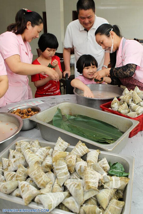 Ni?os así como sus maestros elaboran Zongzi, una bola de masa de arroz glutinoso envuelta en holas de bambú u hojas rojas, con motivo del próximo Festival del Bote de Dragón o Duanwu en chino, en una casa de caridad en Xuchang, provincia de Henan, en el centro de China, el 8 de junio de 2016. El Duanwu se celebrará el 9 de junio este a?o. (Xinhua/Niu Shupei)