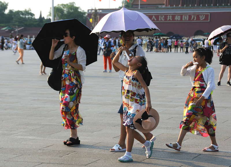 Turistas pasean por la plaza Tian′anmen con paraguas y helados para combatir el calor, el 6 de julio de 2016. [Foto/VCG]