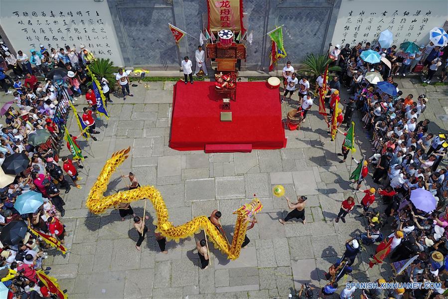 Personas observan una danza del dragón durante una ceremoni del Festival Duanwu, en el Parque del Humedal Nacional Xixi, en Hangzhou, capital de la provincia de Zhejiang, en el este de China, el 30 de mayo de 2017. La ceremonia consite en diversas actividades relacionados en el Festival Duanwu o Festival del Bote del Dragón mientras se lleva a cabo la danza del dragón y competencias de bote de dragón. (Xinhua/Zhang Cheng)