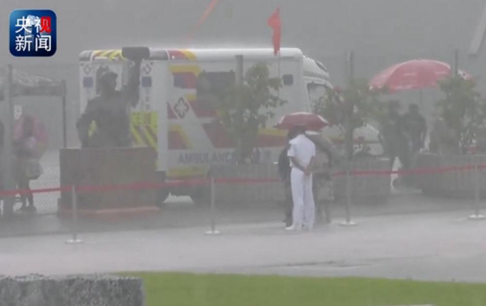 Ciudadana de Hong Kong sostiene un paraguas a un guardia del ELP durante una tormenta