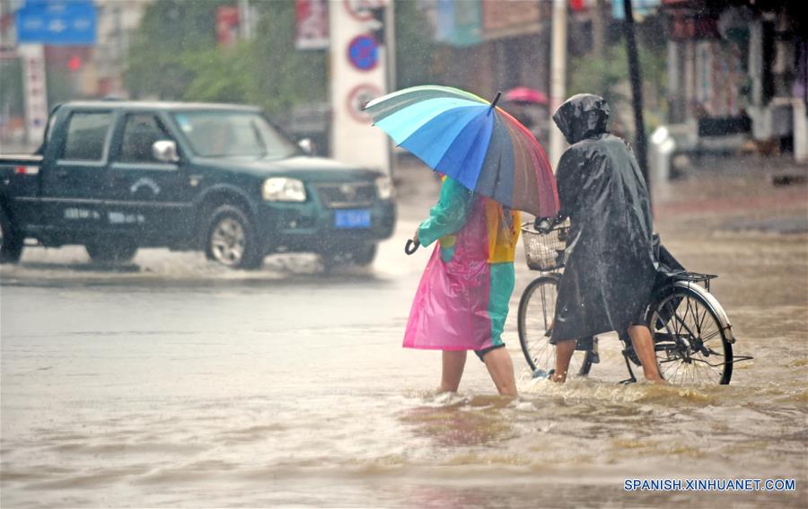 Residentes caminan en una calle inundada, en el condado de Xiuyan de Anshan, en la provincia de Liaoning, en el noreste de China, el 4 de agosto de 2017. Una lluvia torrencial afectó al condado el jueves y viernes, da?ando caminos, instalaciones de electricidad y cultivos en algunos municipios. Un total de 18,900 personas han sido trasladadas a lugares seguros, y la ciudad ha iniciado el nivel 1 de respuesta de emergencias para enfrentar las posibles inundaciones. (Xinhua/Yang Qing)