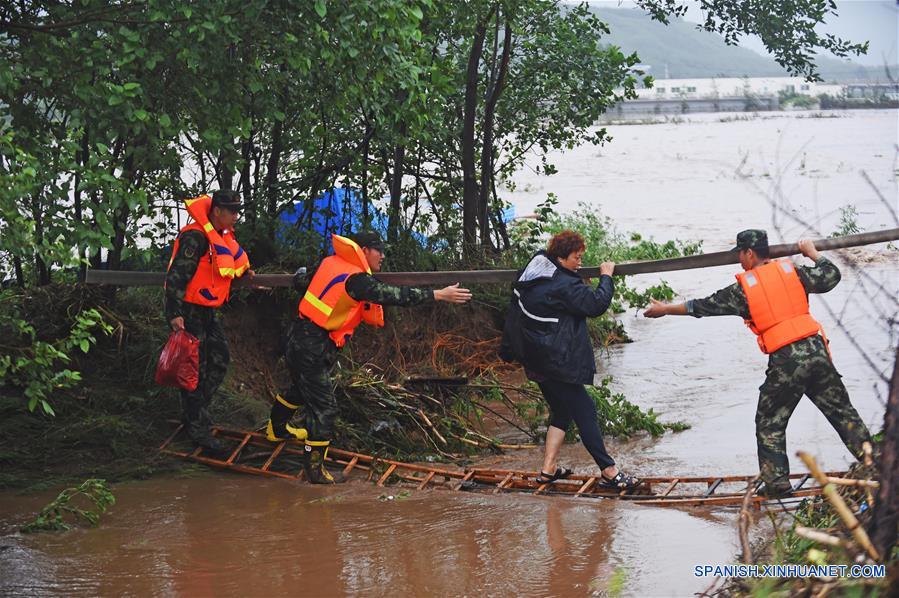 Bomberos rescatan a un poblador en la aldea Bajiapu, en el condado de Xiuyan de Anshan, en la provincia de Liaoning, en el noreste de China, el 4 de agosto de 2017. Una lluvia torrencial afectó al condado el jueves y viernes, da?ando caminos, instalaciones de electricidad y cultivos en algunos municipios. Un total de 18,900 personas han sido trasladadas a lugares seguros, y la ciudad ha iniciado el nivel 1 de respuesta de emergencias para enfrentar las posibles inundaciones. (Xinhua/Yang Qing)