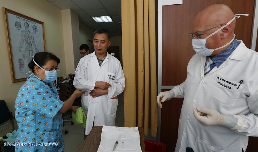 Imagen del 29 de septiembre de 2017, del médico ecuatoriano, Nixon Benavides (d) junto al medico chino Kong De Shu (c), preparándose para aplicar una terapia de medicina tradicional china, en el Hospital Militar, en Quito, Ecuador. (Xinhua/Santiago Armas)