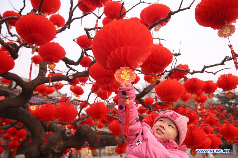 Un ni?o juega con los faroles rojos que embellecen la puerta sur del parque Ditan, conocido también como el parque del Templo de la Tierra, Beijing, 27 de enero del 2018. [Foto: Xinhua]