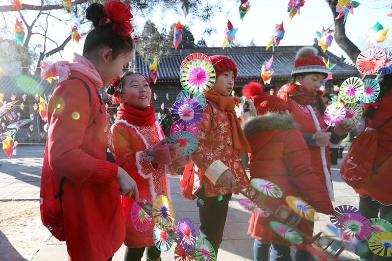 Los ni?os con trajes festivos de colores juegan con molinetes de colores en el Observatorio Antiguo en Beijing para celebrar el periodo del calendario lunar Comienzo de la Primavera, que comenzó el domingo. [Foto de Wang Zhuangfei / chinadaily.com.cn]