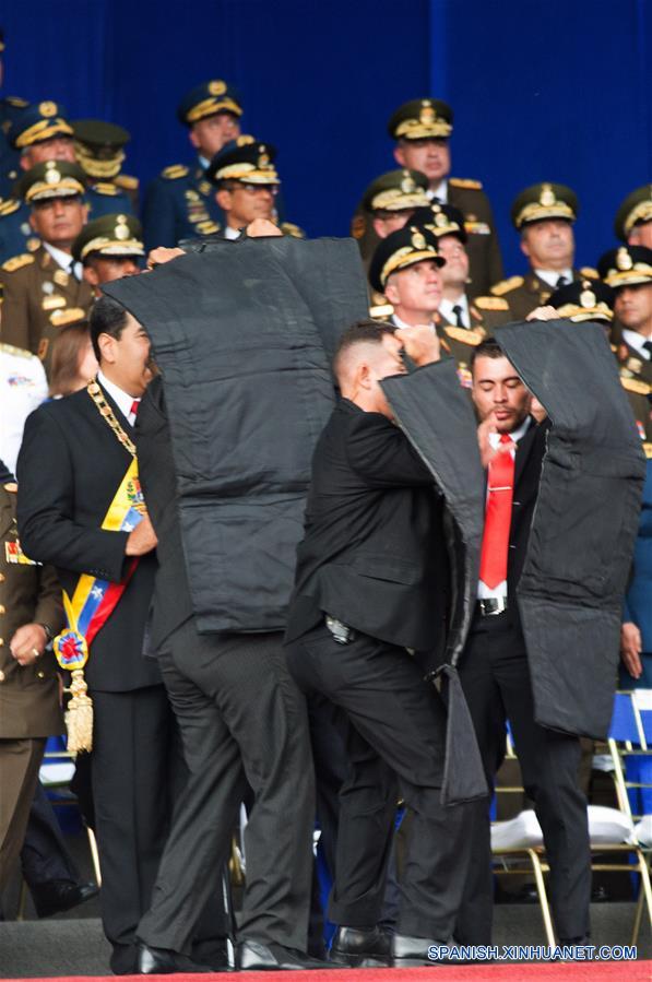 Elementos de seguridad protegen al presidente de Venezuela, Nicolás Maduro, luego que su discurso fuera interrumpido, durante un acto para conmemorar el 81 aniversario de la Guardia Nacional Bolivariana de Venezuela, en la Plaza Bolívar, en Caracas, Venezuela, el 4 de agosto de 2018. Durante una ceremonia conmemorativa del 81 aniversario de la Guardia Nacional Bolivariana de Venezuela en la que ofrecía un discurso el presidente venezolano, Nicolás Maduro, ocurrió el sábado un suceso inesperado que conllevó a la suspensión abrupta de la transmisión y del acto presidencial. Confirman atentado contra presidente Maduro durante acto militar en Caracas. (Xinhua/Str)