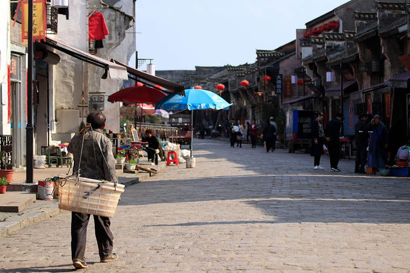 Un agricultor camina por una calle después de vender todas sus verduras en Datong, una antigua ciudad en la orilla oriental del río Yangtze en Tongling, provincia de Anhui, el 25 de marzo de 2019. [Foto por Zhu Lixin / chinadaily.com.cn]