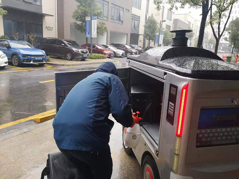 Antes de ponerla en el vehículo no tripulado, un trabajador desinfecta una caja donde depositará la comida solicitada. [Foto: proporcionada a chinadaily] 