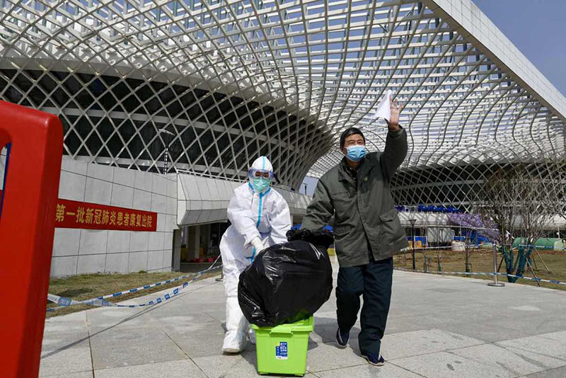 Un trabajador de la salud acompa?a a un hombre del último grupo de pacientes recuperados que fueron dados de alta en el Hospital Jiangxia, un centro médico temporal  operado por profesionales de la medicina tradicional china en la provincia de Hubei, 10 de marzo del 2020. [Foto: Zhu Xingxin/ Chinadaily]