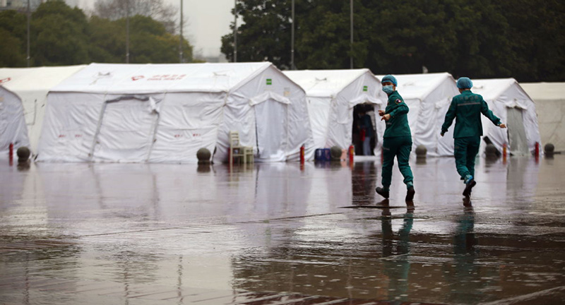 En medio de la lluvia, el último grupo de médicos del Hospital Temporal Jianghan se apresuran hacia las tiendas de campa?a para cambiarse la ropa. (Foto: Zhang Zheng/ China Daily)