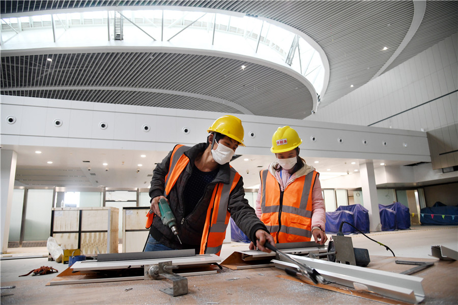 Dos empleados trabajan en el área central del paisaje en el Aeropuerto Internacional Jiaodong de Qingdao, provincia de Shandong, este de China, el 25 de marzo de 2020. [Foto / Xinhua]