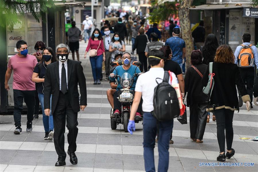 Personas portan mascarillas mientras caminan en una calle en Santiago, capital de Chile, el 21 de abril de 2020. Chile aumentó a 10.832 el número de casos de la enfermedad causada por el nuevo coronavirus (COVID-19), de los cuales 147 han muerto, informó el martes el Ministerio de Salud del país. (Xinhua/Jorge Villegas)