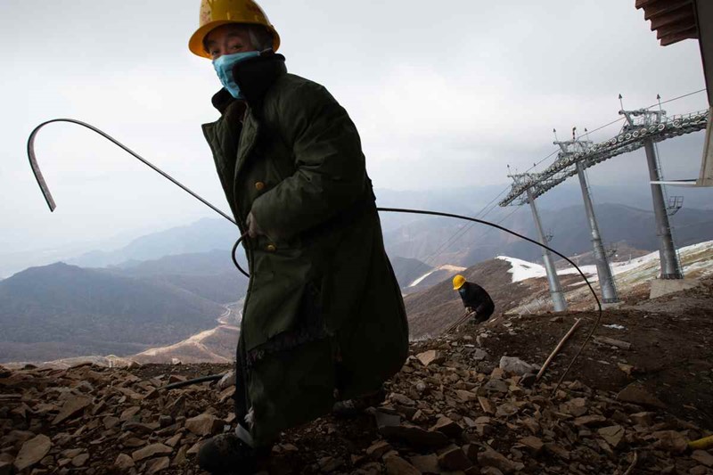 Los trabajadores vestidos con gruesos abrigos limpian los escombros en el sitio de construcción del Centro Nacional de Esquí Alpino en la monta?a Haituo de Yanqing en Beijing el 17 de abril. [Foto de Kuang Linhua / China Daily]