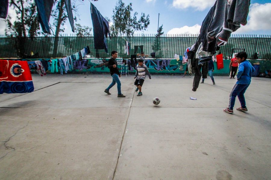 Migrantes juegan al fútbol en el Albergue Nueva Misión Agape, en Tijuana, México, el 4 de abril de 2020. El coronavirus aplazó el proceso de asilo en Estados Unidos de migrantes centroamericanos, sudamericanos y caribe?os que aguardaban en el norte de México, lo que complicó su precaria economía. (Xinhua/Joebeth Terriquez)