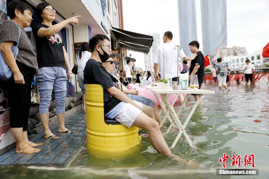 La imagen muestra a los ciudadanos sentados en sillas con los pies sumergiendo en el agua mientras observan la marea. Foto de Li Siyuan, China News Agency.