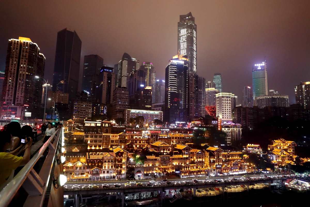 Los visitantes disfrutan de vistas nocturnas de Hongyadong desde el puente Qiansimen sobre el río Jialing, Chongqing. [Foto de Wang Zhuangfei / China Daily]