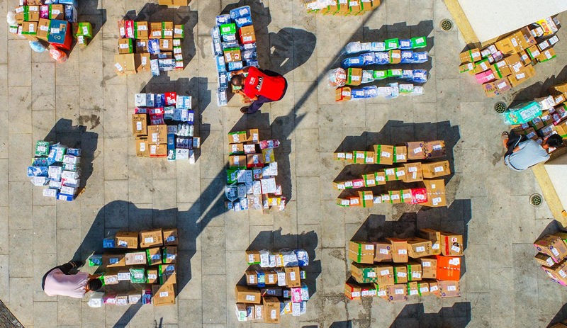 Imagen de varios repartidores ordenando los paquetes de entrega exprés en la entrada de la Universidad de Hainan, el 13 de noviembre. Por Zhang Mao / vip.people.com.cn