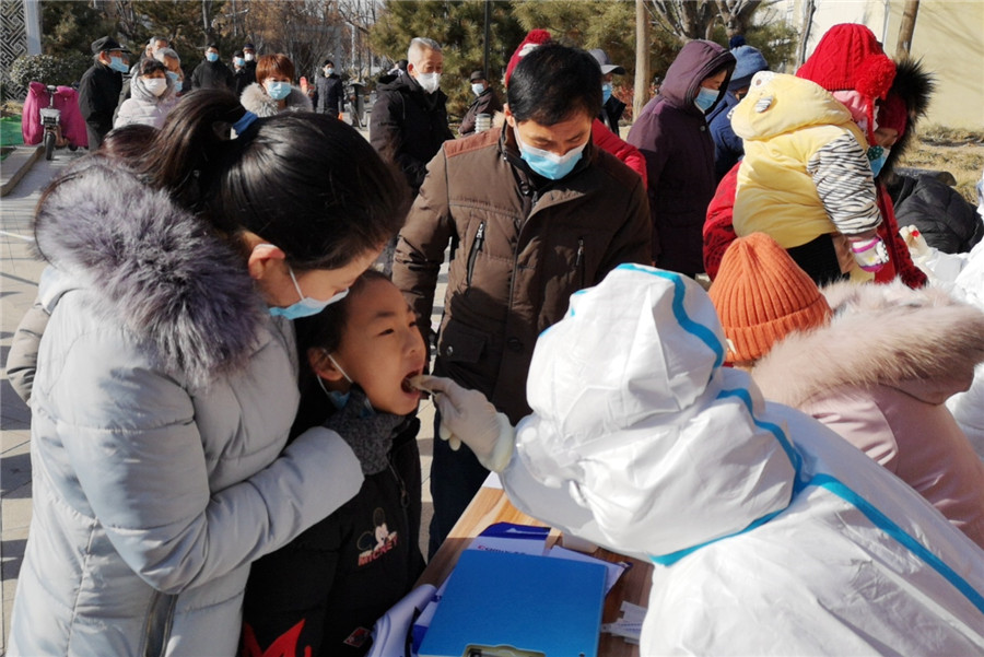 Un trabajador médico toma una muestra de garganta de una ni?a en una comunidad residencial en Xingtai, provincia de Hebei, el 6 de enero de 2021. [Foto de Huang Tao / Para China Daily]