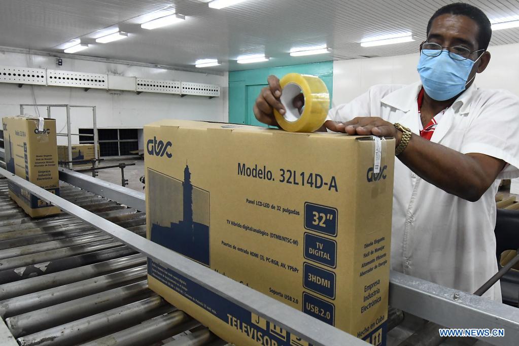 Imagen del 21 de mayo de 2021 de un trabajador empacando un televisor en los talleres de la Empresa Industria Electrónica "Comandante Camilo Cienfuegos", en La Habana, capital de Cuba. Cuba espera dar un impulso a la expansión de la televisión digital con norma china mediante la producción este a?o de 318.000 cajas decodificadoras, en el contexto de la pandemia de la enfermedad del nuevo coronavirus (COVID-19) y los efectos de las sanciones económicas del bloqueo de Estados Unidos contra el país. (Xinhua/Joaquín Hernández)