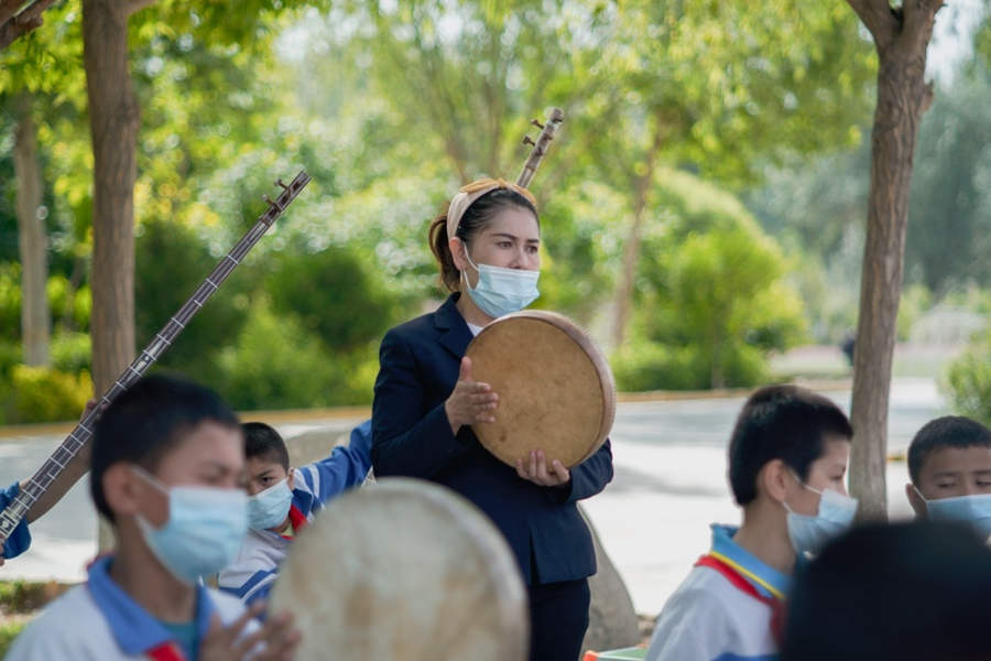 Una maestra imparte clases de instrumentos tradicionales a estudiantes Uygur en la escuela primaria central de Awati en Kashgar, en la región autónoma Uygur de Xinjiang en el noroeste de China, el 19 de mayo de 2021. La escuela primaria central de Awati tiene más de 2.700 estudiantes, todos de la etnia Uygur. (Pueblo en Línea / Ma Tianyi)