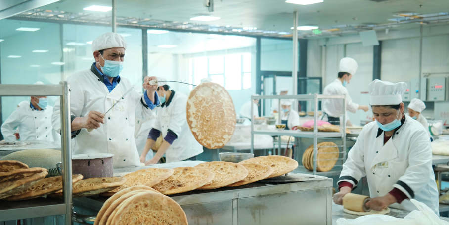 Panaderos en un parque industrial preparan pan Nang, una especie de torta crujiente, en Kashgar, en la región autónoma Uygur de Xinjiang, noroeste de China, el 20 de mayo de 2021. Nang, un pan plano horneado, es el alimento básico de la etnia Uygur. (Pueblo en Línea / Zhang Ruohan)