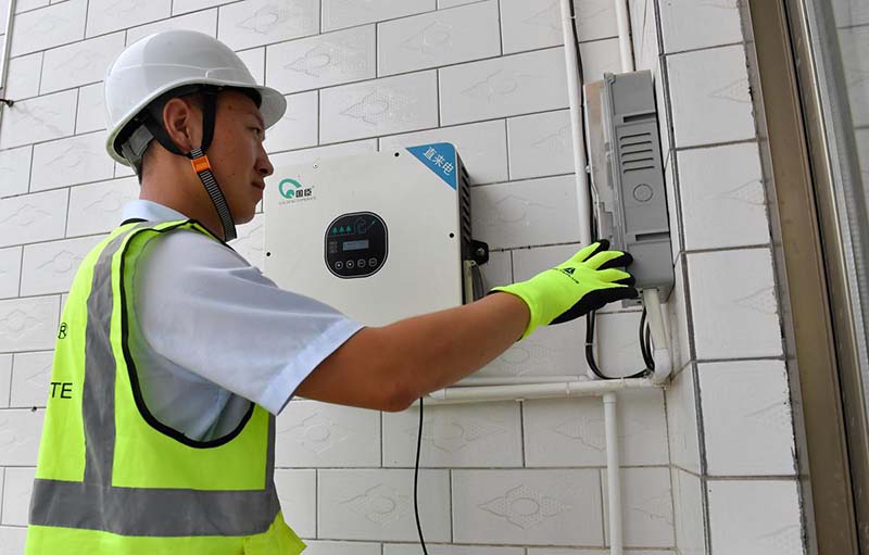 Un miembro del personal de Golden Cooperate Information & Automation Technology Co examina el nuevo sistema de energía solar en la aldea de Zhuangshang en Yuncheng, provincia de Shanxi. [Foto de Xiao Yongjie / para chinadaily.com.cn]