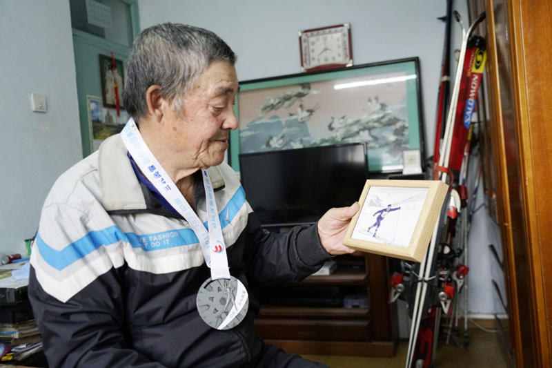 Han Tongyuan ense?a una vieja foto donde aparece esquiando en su casa de Jilin. [Foto: Zhang Yichi/ China Daily]