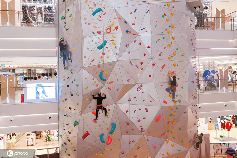 Los entusiastas de los deportes extremos experimentan la escalada en roca en un centro comercial de Shanghai, 19 de diciembre del 2021. [Foto: IC]