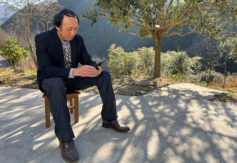 Foto tomada el 5 de diciembre del 2021 que muestra a Liu Wenguo desplazándose con su teléfono en el patio de la casa de la familia. (Foto: Pueblo en Línea/ Meng Bin)