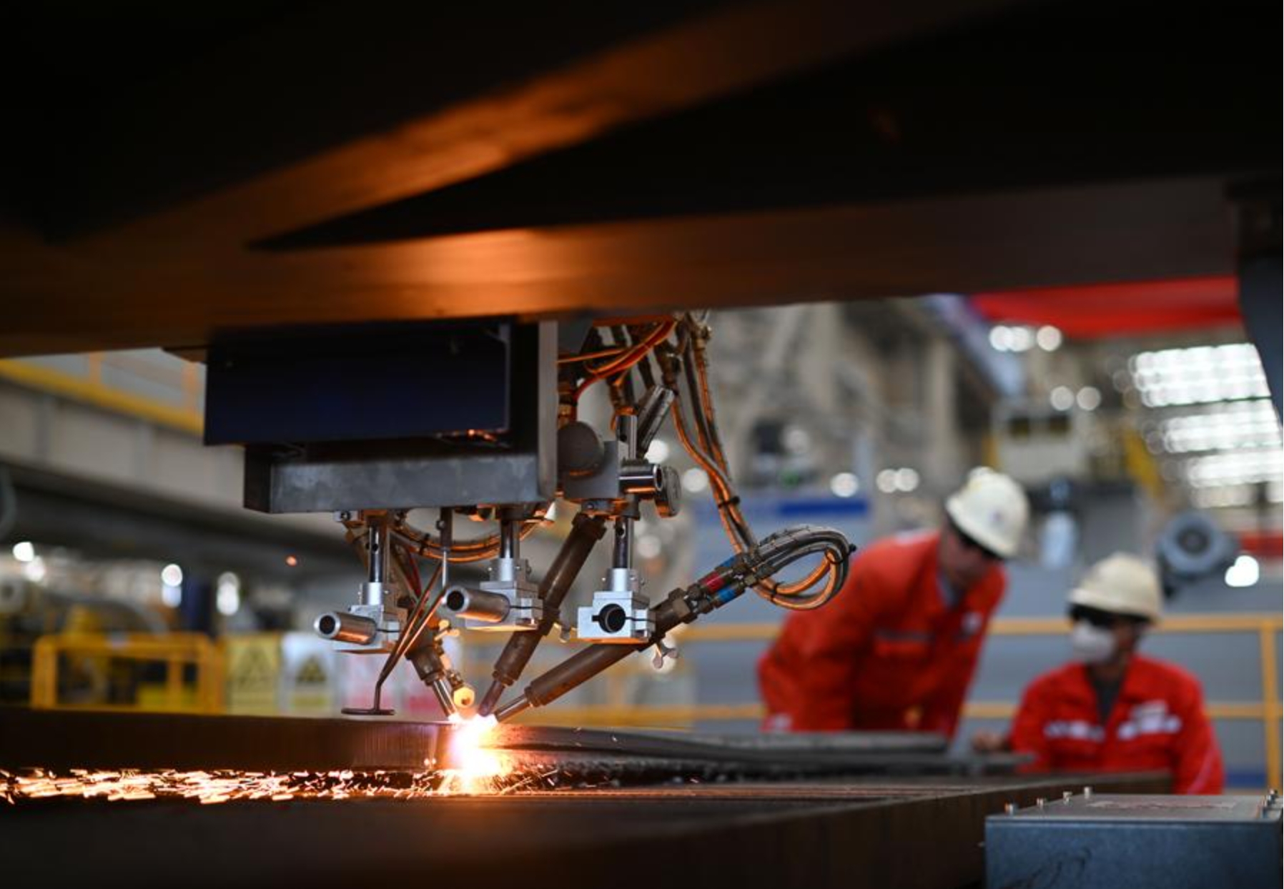 Trabajadores depuran una máquina cortadora de placas digital en un taller de tuberías de una base de fabricación inteligente de China Offshore Oil Engineering Company, en Tianjin, en el norte de China, el 30 de octubre de 2024. (Xinhua/Zhao Zishuo)