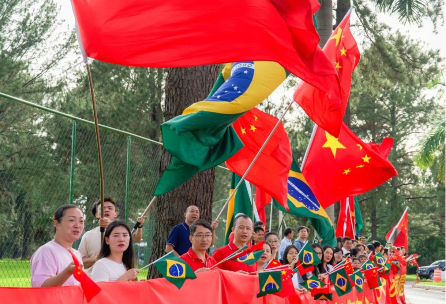 Representantes de chinos de ultramar, instituciones y estudiantes chinos ondean las banderas nacionales de China y Brasil en la carretera, felicitando al presidente chino, Xi Jinping, por el completo éxito de la visita, mientras la comitiva de Xi se traslada al aeropuerto, en Brasilia, Brasil, el 21 de noviembre de 2024.(Xinhua/Wang Tiancong)