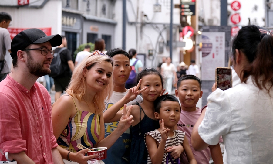 Turistas extranjeros se toman fotos con turistas chinos en un barrio tradicional de Changsha, provincia de Hunan, 28 de agosto del 2024. (Foto: China Daily) 